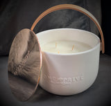 Indulge in the Bergamot and Clove Perfumed Estate Candle from One Preevay. Handcrafted with premium essential oils and soy wax, it features a stunning porcelain bowl with a silver-plated lid and leather strap. Elevate your ambiance with leather and porcelain
