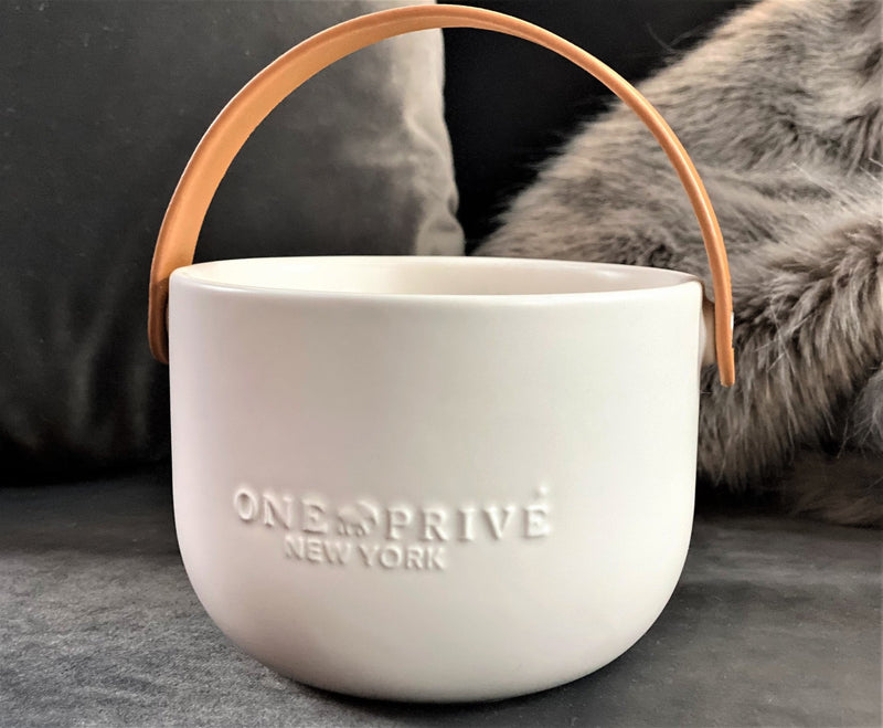 Indulge in the Bergamot and Clove Perfumed Estate Candle from One Preevay. Handcrafted with premium essential oils and soy wax, it features a stunning porcelain bowl with a silver-plated lid and leather strap. Elevate your ambiance so elegant 